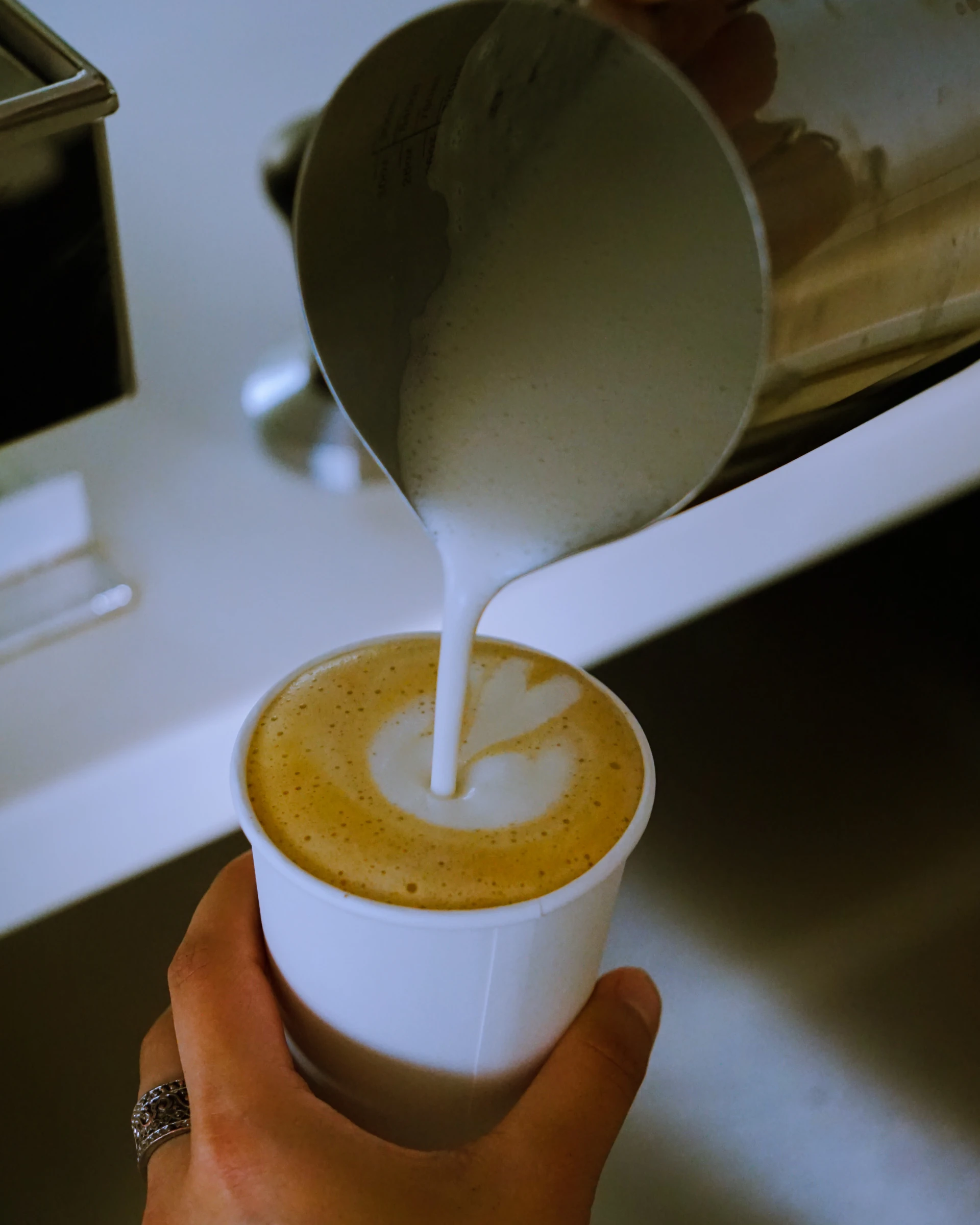 A Mi Manera barista pouring steamed milk into a latte
